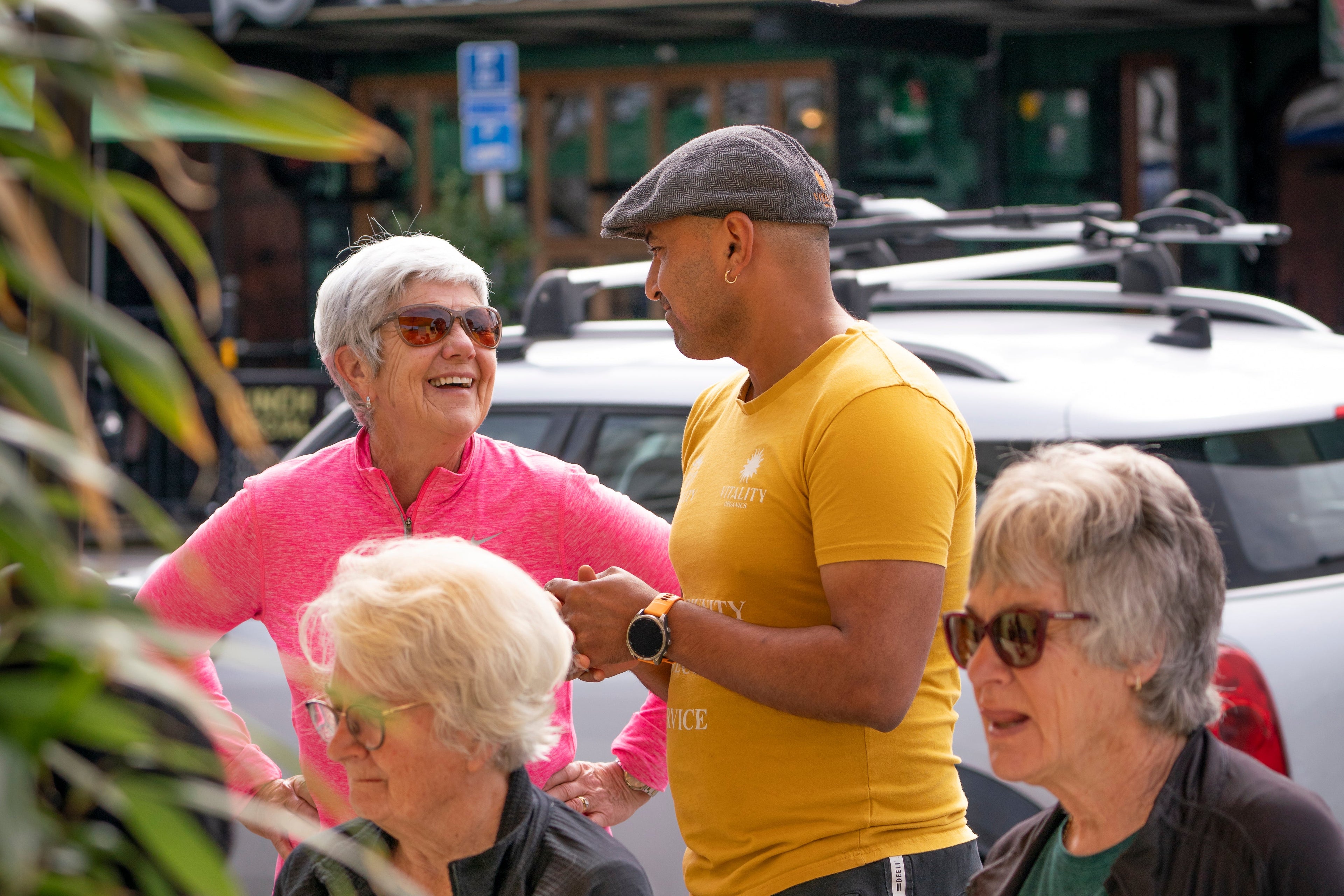 Group of people sitting at an outdoor table with a yellow umbrella and urban background